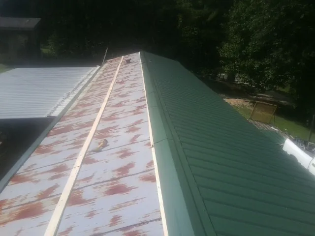 Old rusted panels beside newly installed green metal roofing — Wind Damage Roof Repair by Roofing Brothers in Eufaula