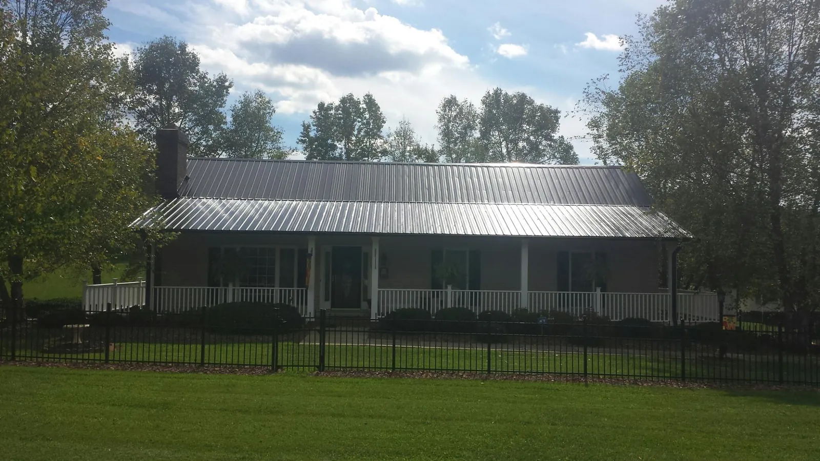 Gray metal roof on a brick ranch with a full width front porch — Gutter Guard Installation work by our crew in Eufaula